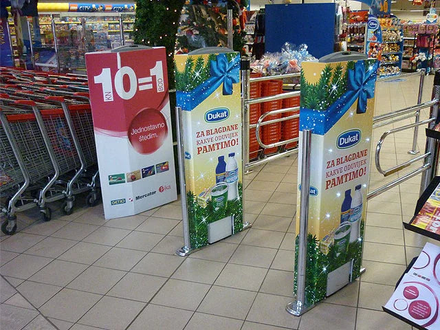 In-store advertising displays with holiday-themed posters near shopping carts in a supermarket