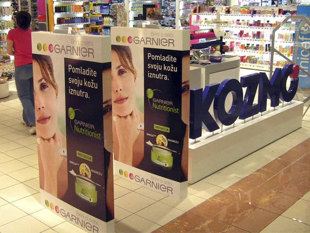 In-store advertising display for Garnier skincare products in a cosmetics shop with product shelves.